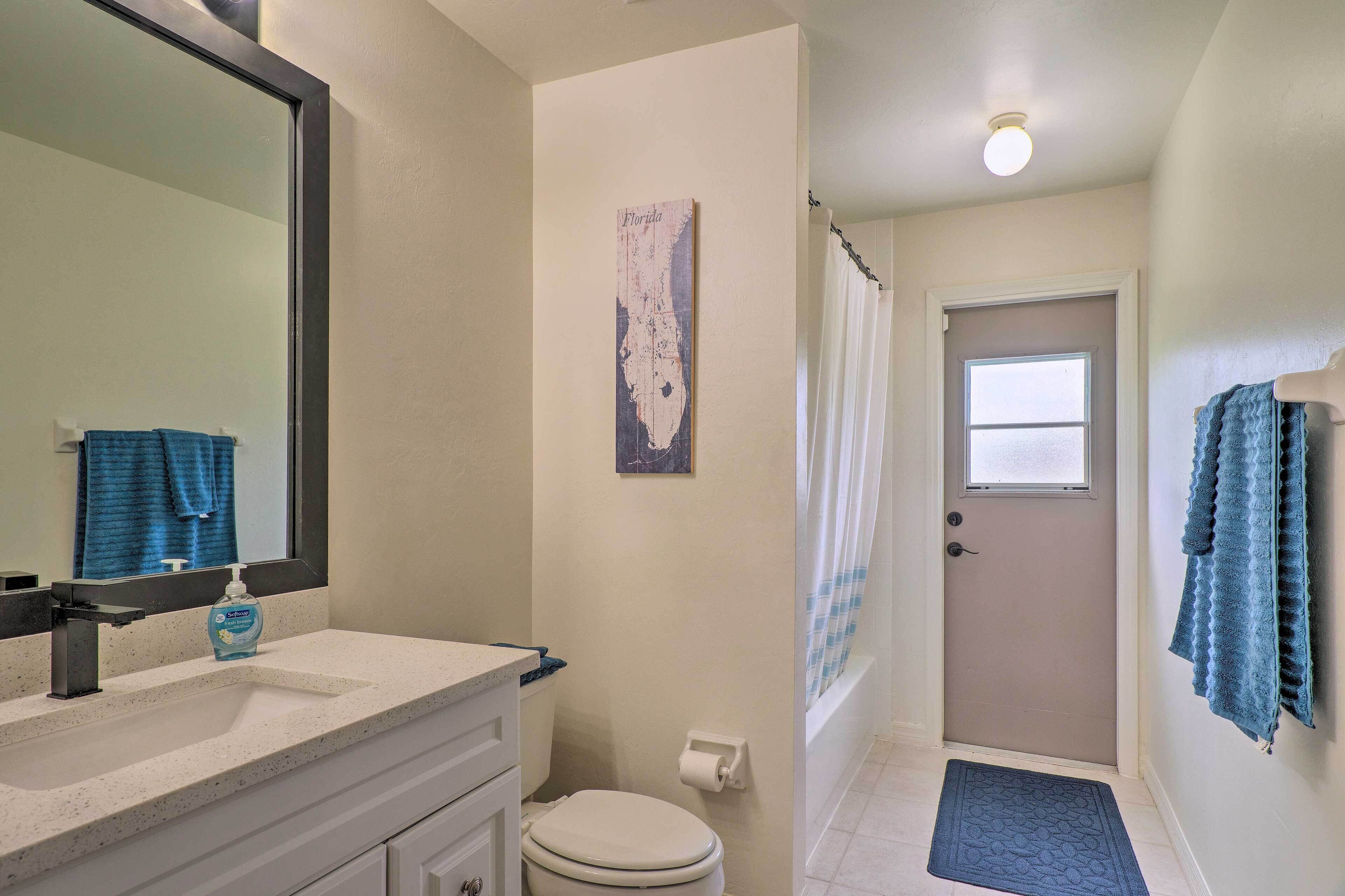 A bathroom with a white sink, a toilet, a shower curtain, and a door with a window.