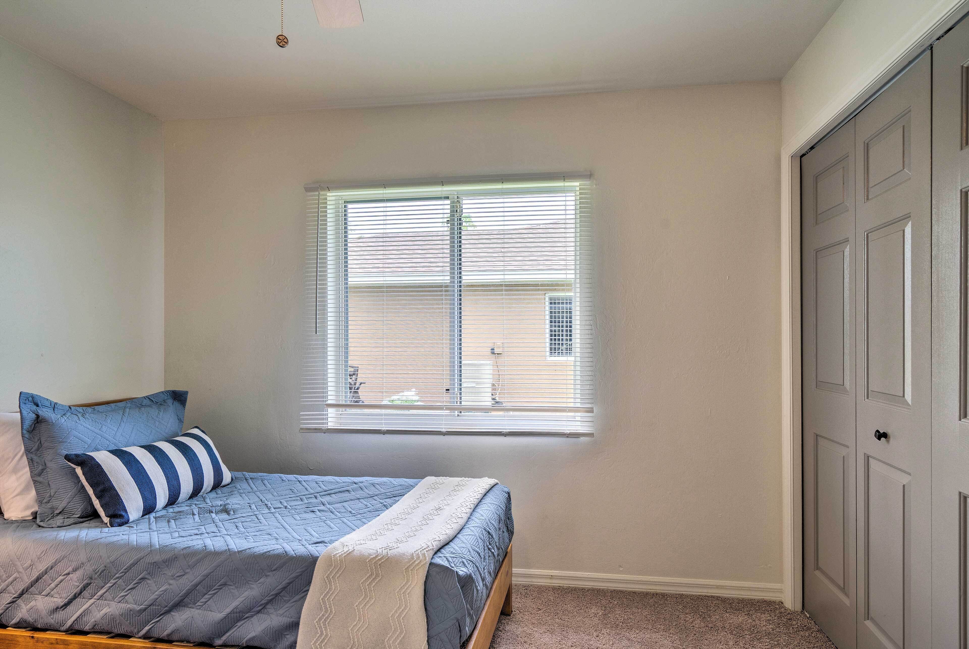A bedroom with a bed, a window, and a door.