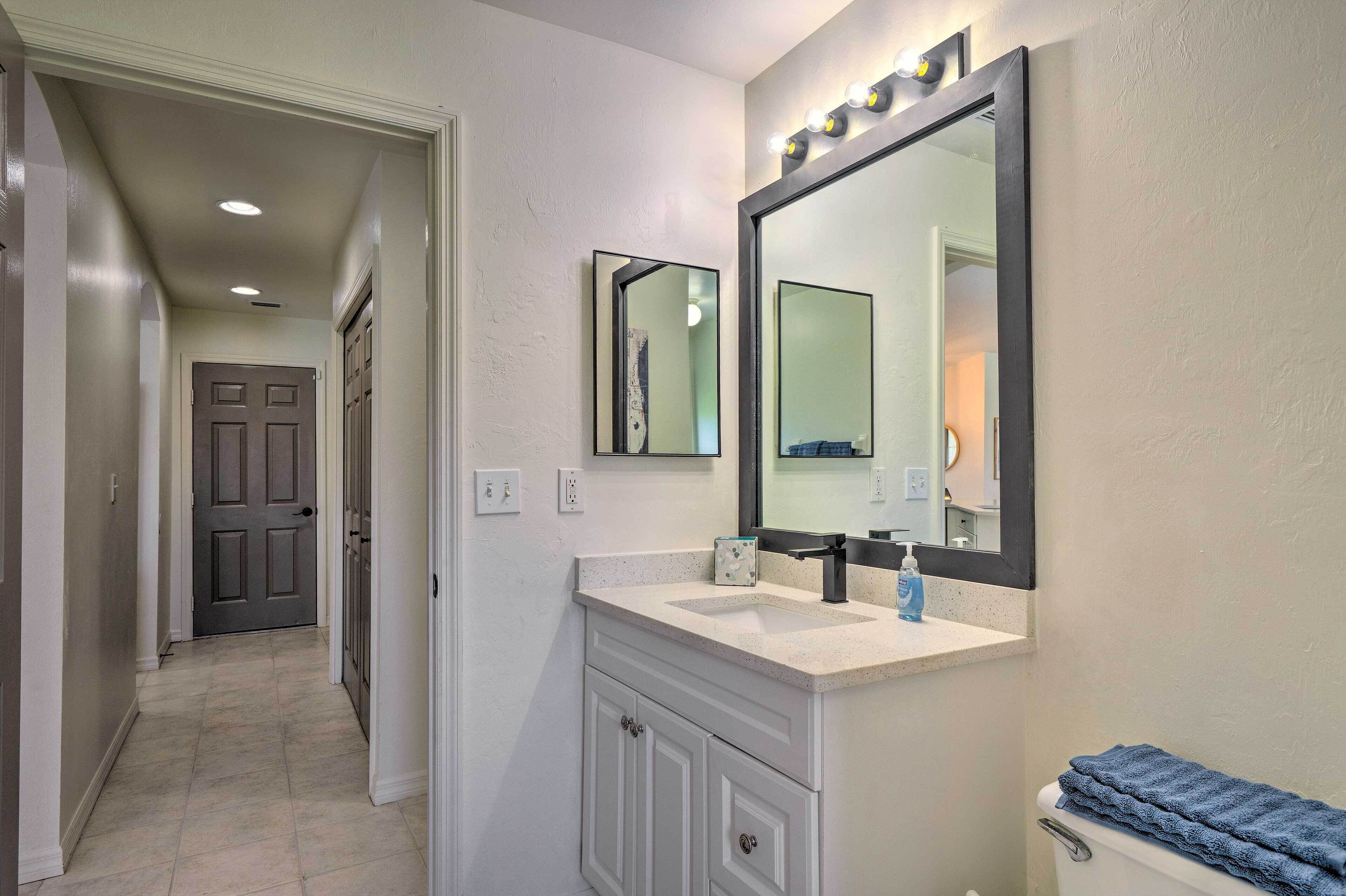 A bathroom with a large mirror, a sink, and a toilet.