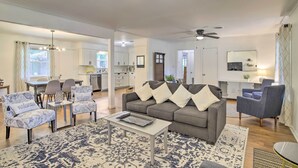 A modern living room with a grey sofa, patterned armchairs, a coffee table, and a dining area with a chandelier. - 1 Mi to Main St: Brenham Retreat w/ Game Room (Brenham)