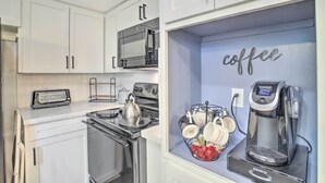 A kitchen with white cabinets, a stove, a microwave, and a coffee machine. - 1 Mi to Main St: Brenham Retreat w/ Game Room (Brenham)