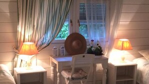 A cozy bedroom with a checkered floor, a bed, a desk with a chair, two bedside lamps, and a window with curtains.