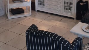 A living room with a flat-screen TV, two lamps, a white cabinet, and a striped sofa.