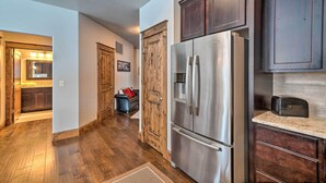 A kitchen with wooden cabinets, a stainless steel refrigerator, and a tiled backsplash. - Main St Bozeman Condo - Walk to Parks & Eateries! (Bozeman)