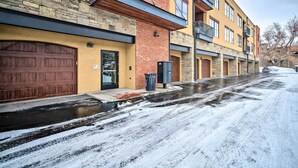 A multi-story residential building with a stone facade, wooden garage doors, and a brick entrance. - Main St Bozeman Condo - Walk to Parks & Eateries! (Bozeman)