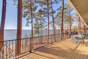 A wooden deck with a railing overlooking a beach and a body of water.