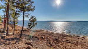 Ranta, jonka yllä on kirkas taivas, aurinko paistaa ja meri on tyyni.