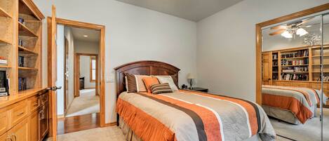 A bedroom with a large bed, wooden headboard, a wardrobe, and a mirror.