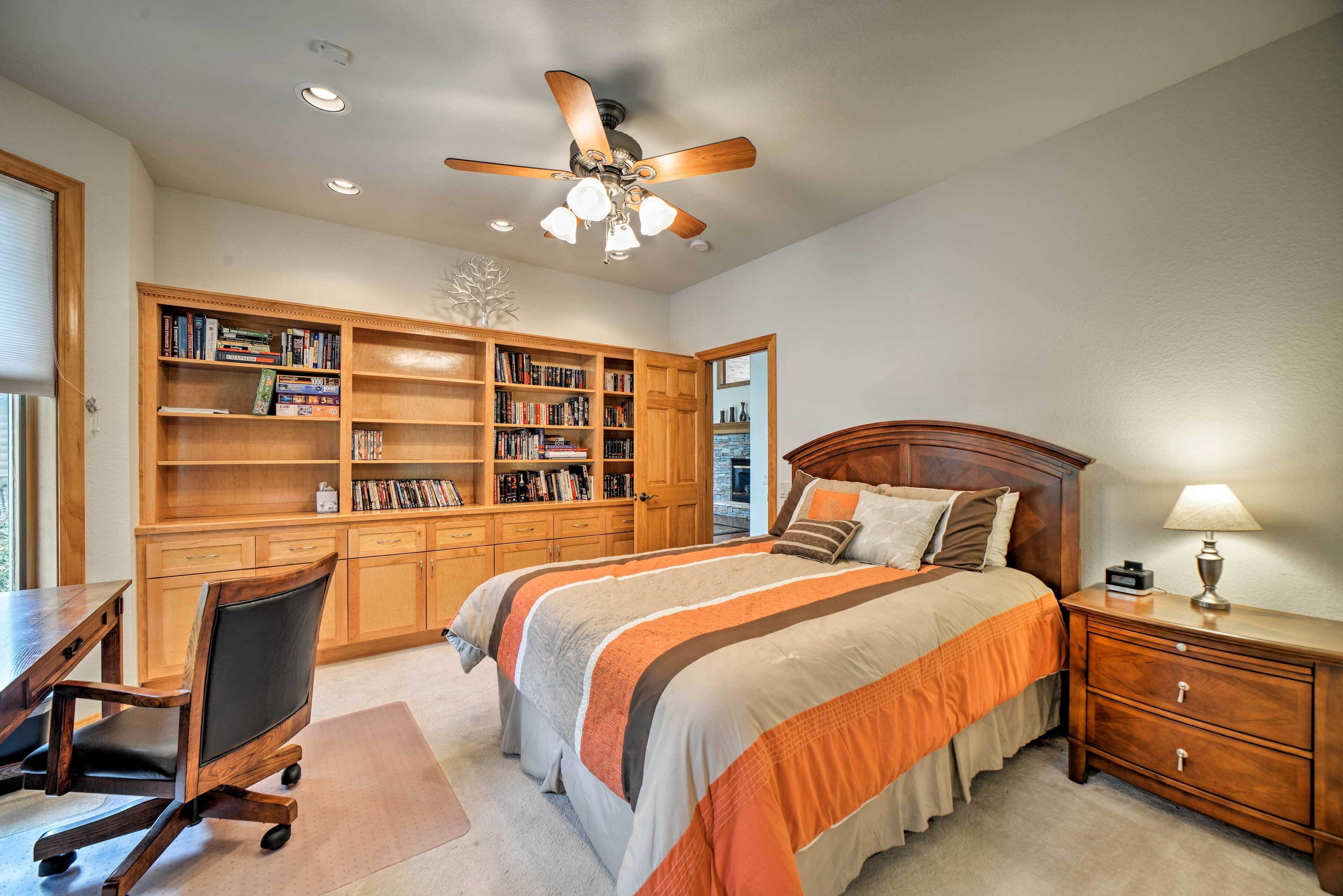 A bedroom with a large bed, a desk, and a bookshelf.
