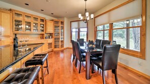 A spacious kitchen with wooden cabinets, a dining table with chairs, and large windows offering a view of the outdoors. - Pagosa Springs Home w/ Patio, Grill & Hot Tub! (Pagosa Springs)