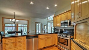 A modern kitchen with wooden cabinets, stainless steel appliances, and a large island with a dishwasher. - Pagosa Springs Home w/ Patio, Grill & Hot Tub! (Pagosa Springs)