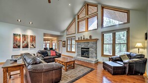 A spacious living room with a stone fireplace, leather sofas, and large windows offering natural light. - Pagosa Springs Home w/ Patio, Grill & Hot Tub! (Pagosa Springs)