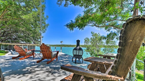 A wooden deck with Adirondack chairs and a lantern, overlooking a lake. - Lakefront Brownwood Home w/ Private Boat Dock (Brownwood)