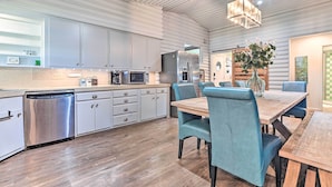 A modern kitchen with stainless steel appliances, a dishwasher, and a dining area with a wooden table and blue upholstered chairs. - Lakefront Brownwood Home w/ Private Boat Dock (Brownwood)