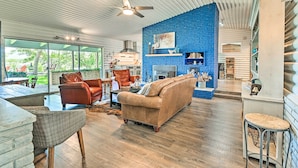 A spacious living area with a blue brick accent wall, leather furniture, and a modern kitchen in the background. - Lakefront Brownwood Home w/ Private Boat Dock (Brownwood)