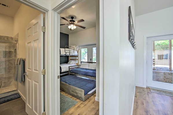 A room with bunk beds, a ceiling fan, and a view of the outdoors. - Modern Cedar Creek Lake Retreat w/ Panoramic View! (Malakoff)