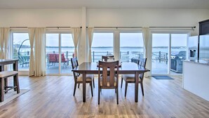 A spacious dining area with a wooden table and chairs, large windows with curtains, and a view of the water. - Modern Cedar Creek Lake Retreat w/ Panoramic View! (Malakoff)
