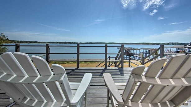 A wooden deck with Adirondack chairs overlooking a lake. - Modern Cedar Creek Lake Retreat w/ Panoramic View! (Malakoff)