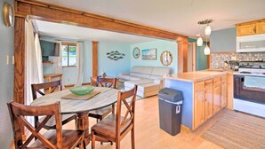 A dining area with a wooden table and chairs, a kitchen with wooden cabinets and a stove, and a living room with a sofa and a painting on the wall. - Riverfront Apt w/ Kayak Launch in Dunnellon (Dunnellon)