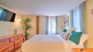 A bedroom with a bed, wooden dresser, potted plant, and a TV mounted on the wall. - Riverfront Apt w/ Kayak Launch in Dunnellon (Dunnellon)