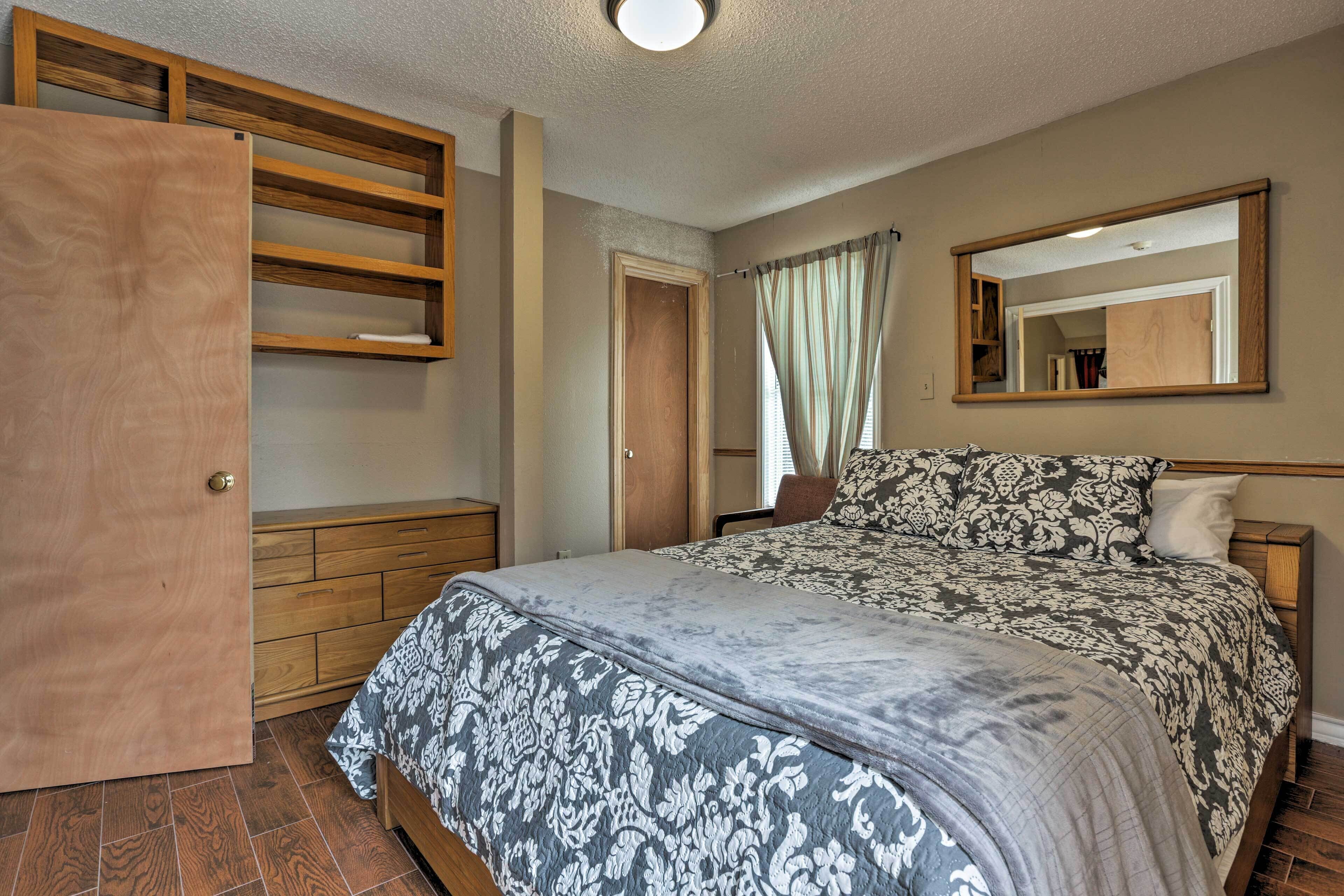Una camera da letto con un letto, un armadio in legno, uno specchio e una porta.