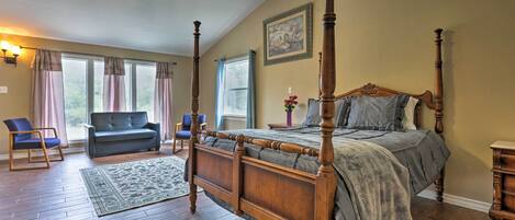 A four-poster bed with a wooden frame, a ceiling fan, and a large window with curtains.