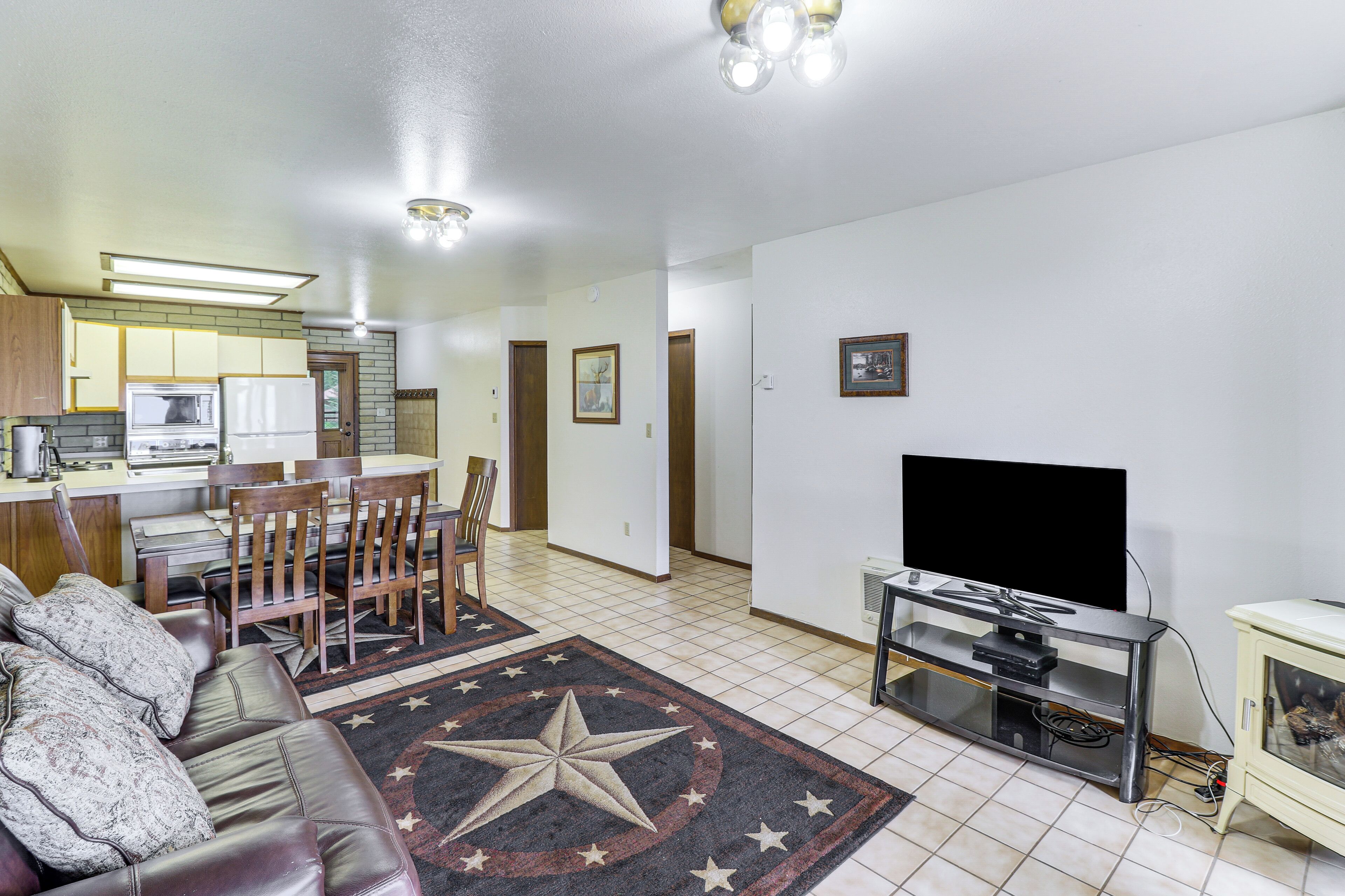 A living room with a sofa, TV, and a star-patterned rug.