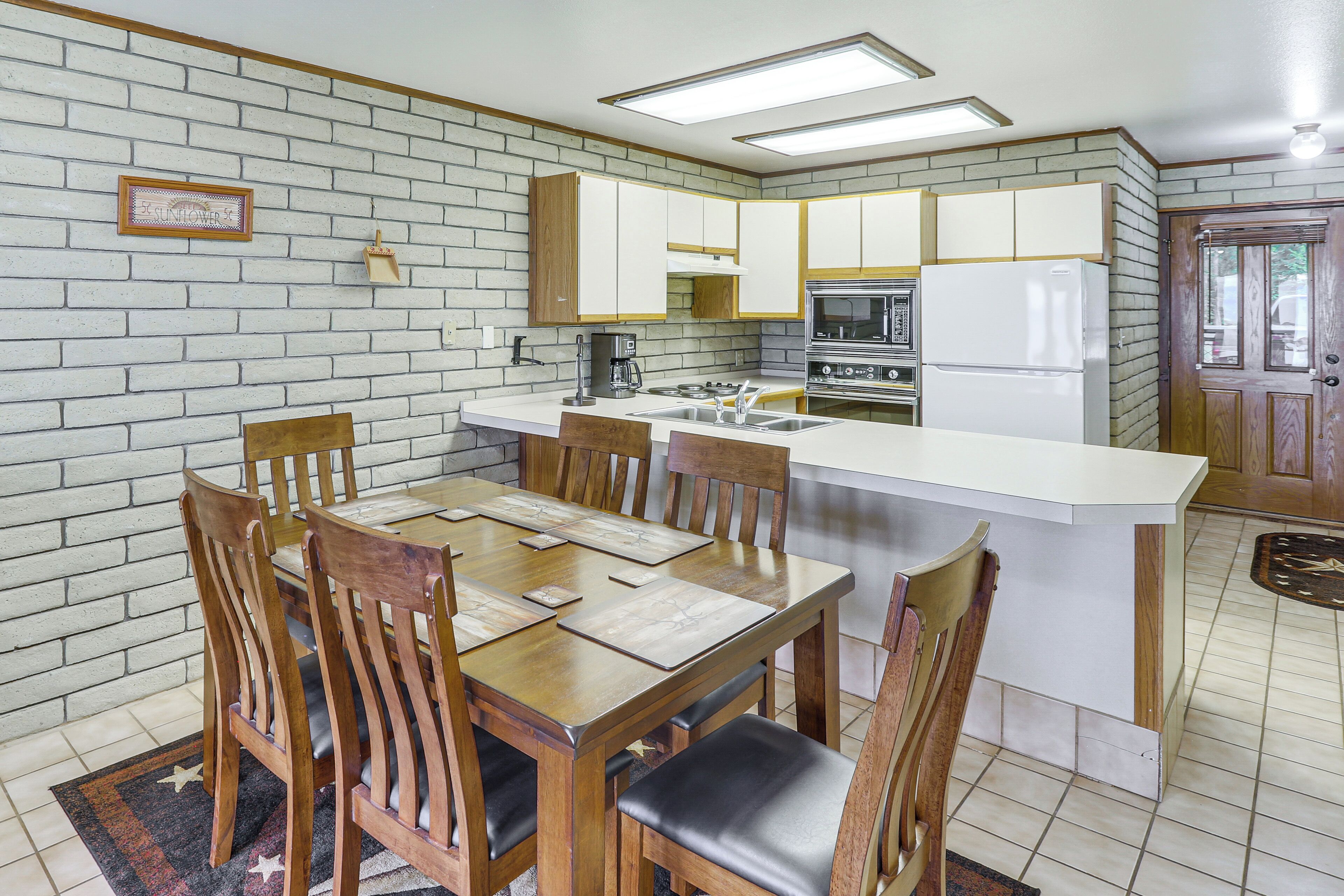 A compact kitchen with white cabinets, a central island, and a dining area with wooden chairs.