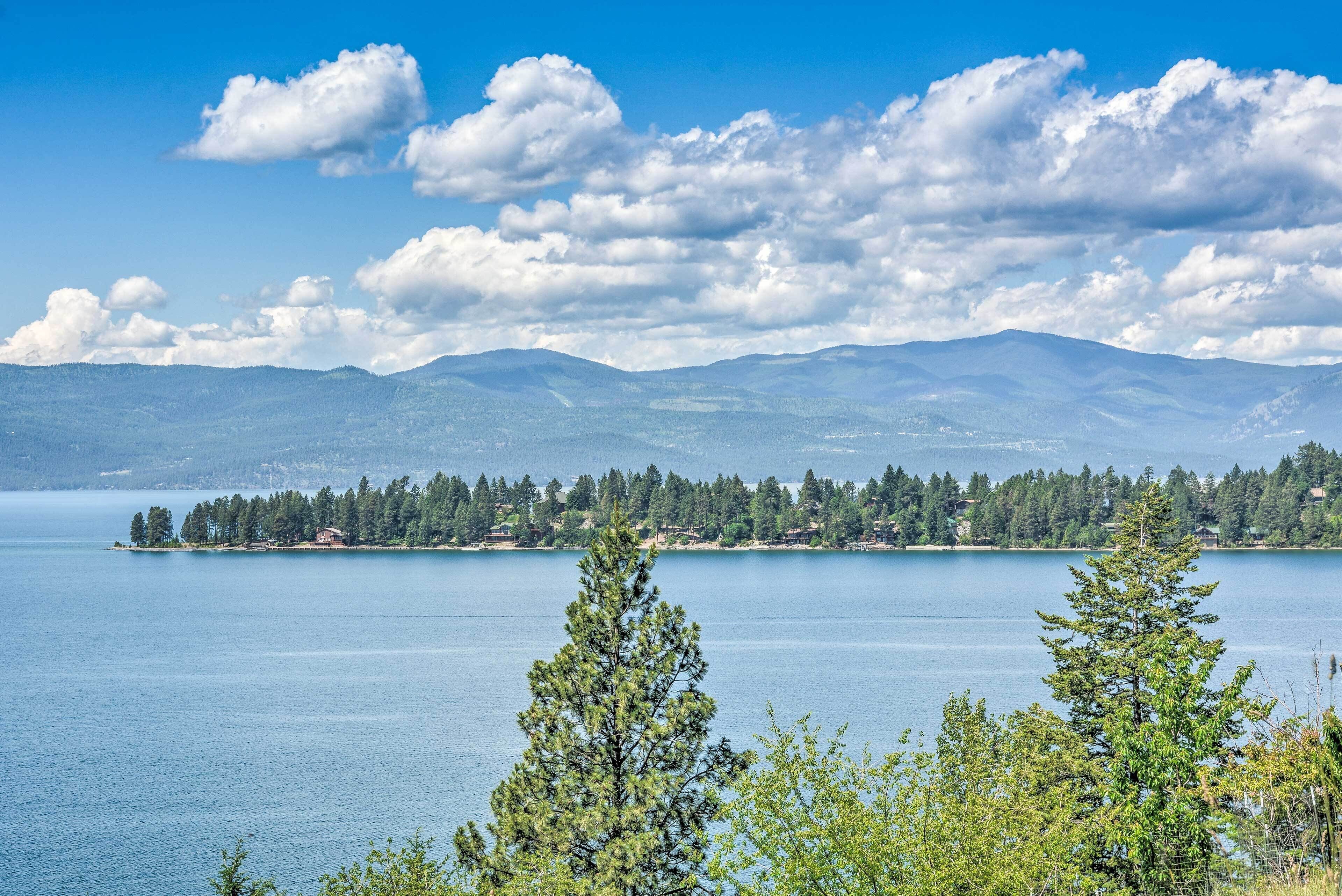 A lake with a forested island and mountains in the background.