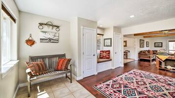 A spacious hallway with a bench, a patterned rug, and a door leading to another room.