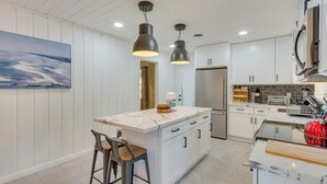 A modern kitchen with white cabinetry, a marble island, and pendant lighting. - Stylish Pensacola Retreat w/ Patio & Grill! (Pensacola)