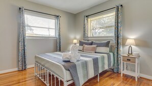 A bedroom with a bed, two bedside tables, a window with blinds, and a curtain. - Stylish Pensacola Retreat w/ Patio & Grill! (Pensacola)