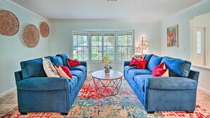 A living room with two blue sofas, a round coffee table, and a patterned rug.