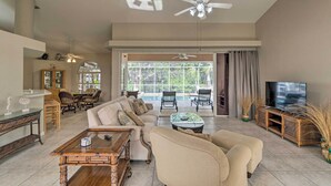Un salon spacieux avec un canapé, une table basse et un meuble pour la télévision. Il y a également un coin repas avec des chaises et une table, ainsi qu’un balcon avec vue.