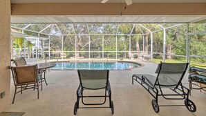 Un espace extérieur abrité comprenant une piscine, des chaises et un ventilateur de plafond.