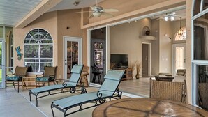 Une véranda avec des fauteuils, une table ronde et un ventilateur de plafond.