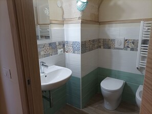A bathroom with a white sink, a toilet, and a shower area. - Casa Kalu' (Crispiano)