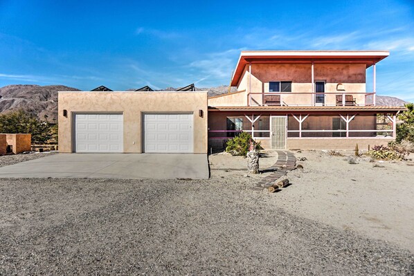 A two-story house with a garage, a balcony, and a desert landscape in the background. - Borrego Springs Home w/ Desert & Mountain Views! (Borrego Springs)