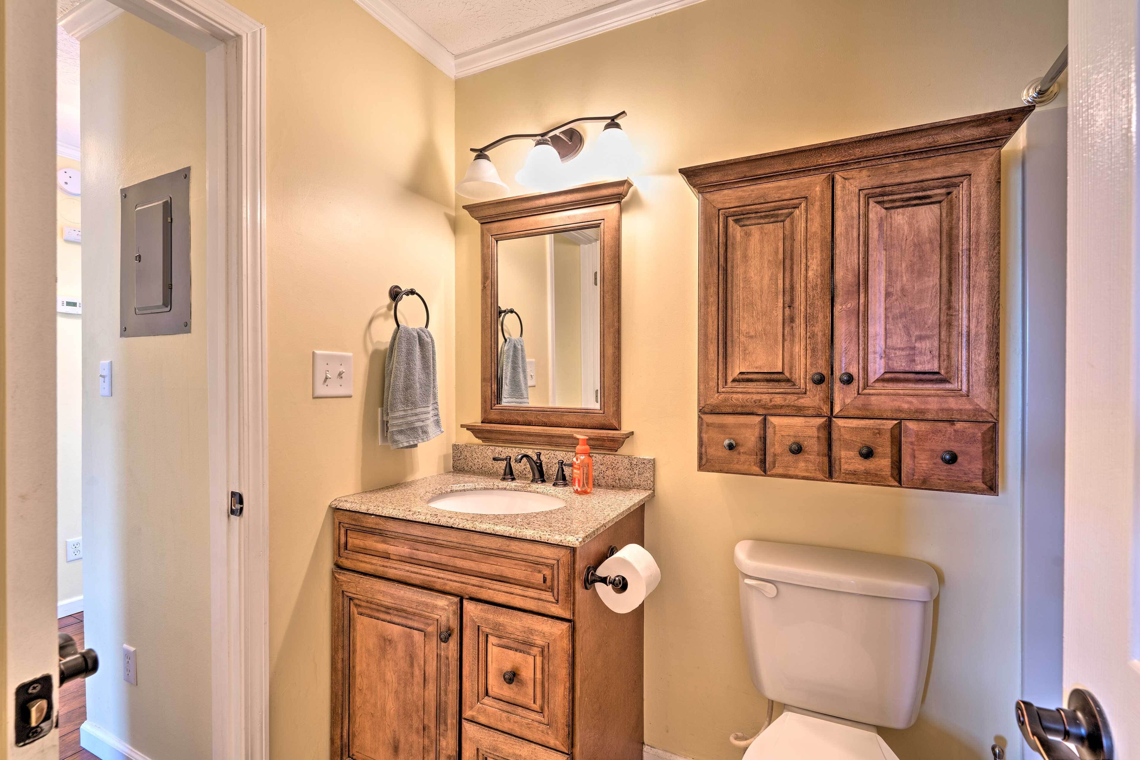 Une salle de bain avec des meubles en bois, un lavabo, des toilettes et un miroir avec éclairage.