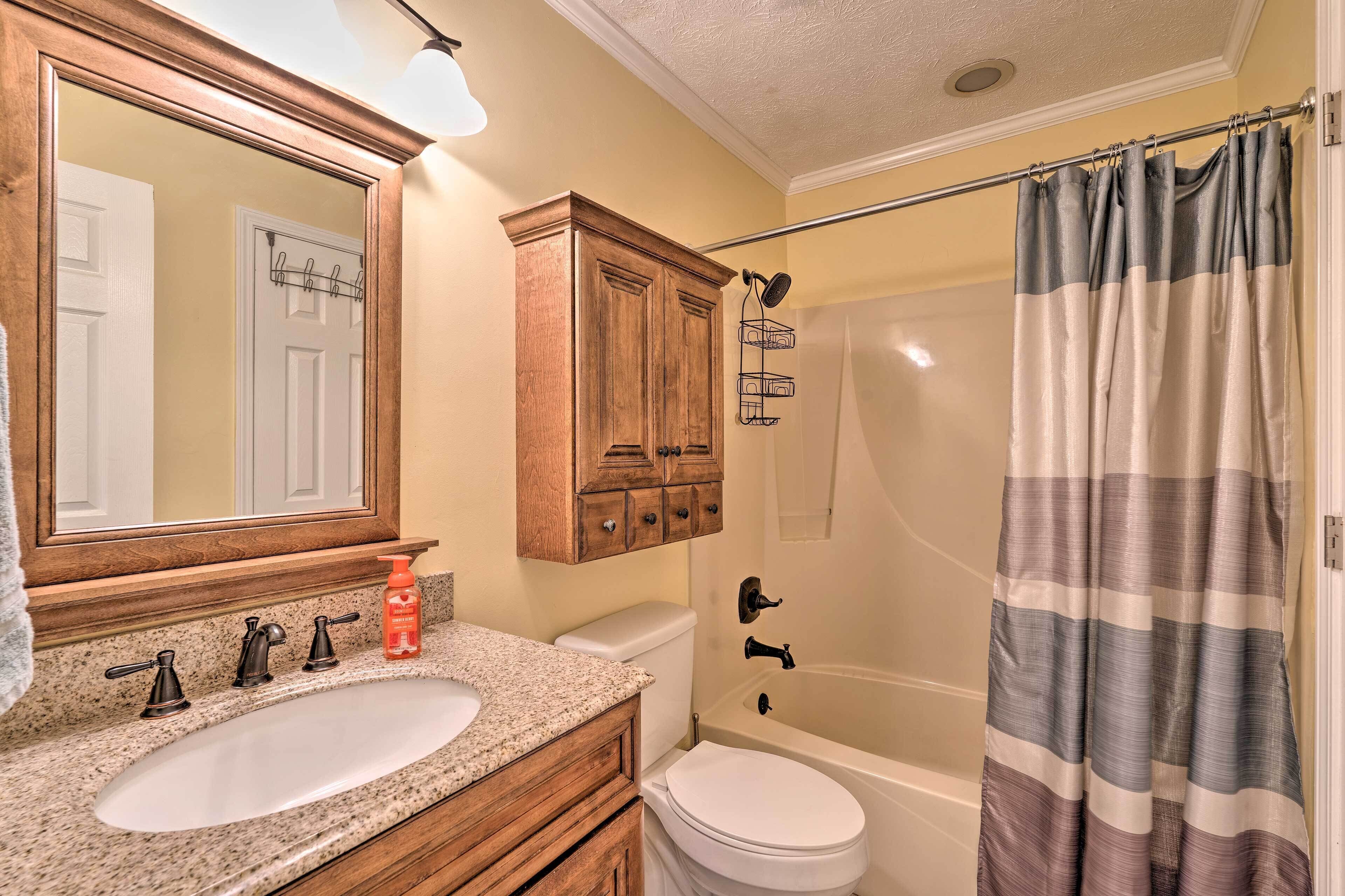 A bathroom with a wooden vanity, a sink, a toilet, and a shower area.