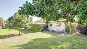 Un immobile residenziale con un prato ben curato, un piccolo albero e una casa con facciata bianca e tetto scuro.