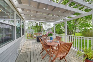 A covered outdoor deck with a wooden table and chairs, surrounded by white railings and large windows. - Rockland Home w/ Deck 5 Mins to Historic Downtown! (Rockland)