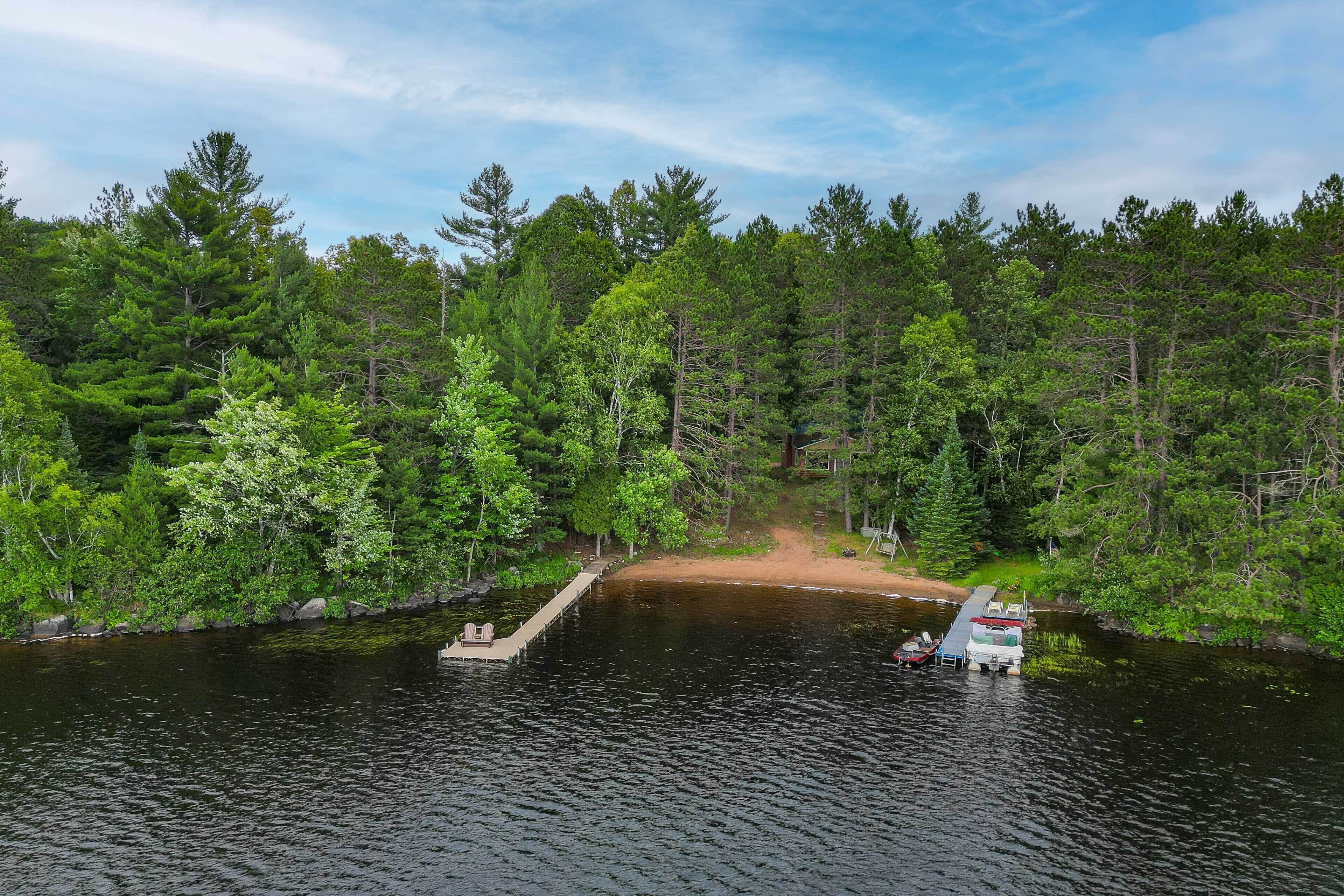 A lake surrounded by dense forest, a dock, and a small boat.