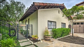 A two-story house with a stone pathway leading to the entrance, surrounded by greenery and a metal gate. - Rancho Santa Fe Casita - Gate Guarded Community! (Escondido)