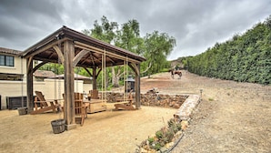 A covered outdoor seating area with wooden furniture and a stone wall. - Rancho Santa Fe Casita - Gate Guarded Community! (Escondido)