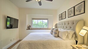 A bedroom with a bed, a ceiling fan, a TV, a window, and framed pictures on the wall. - Rancho Santa Fe Casita - Gate Guarded Community! (Escondido)