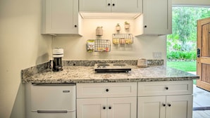 A kitchen with white cabinets, a granite countertop, a coffee maker, a scale, and small potted plants. - Rancho Santa Fe Casita - Gate Guarded Community! (Escondido)