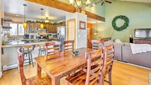 A spacious kitchen with wooden cabinets, a dining area with a wooden table and chairs, a living room with a sofa and a television, and a ceiling fan. - Silverthorne Ski Base w/ Mtn Views: Walk to Trails (Silverthorne)