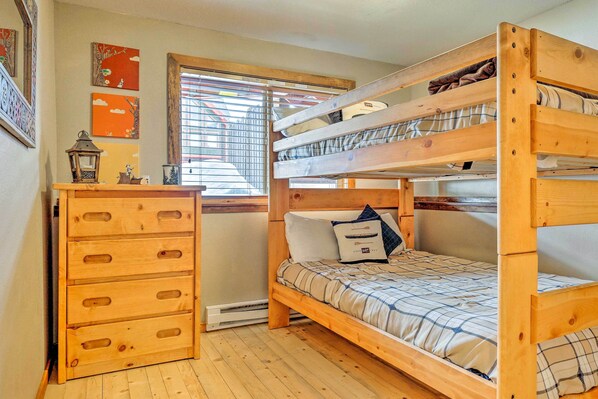 Habitación con literas, cómoda de madera y ventana con persianas.
