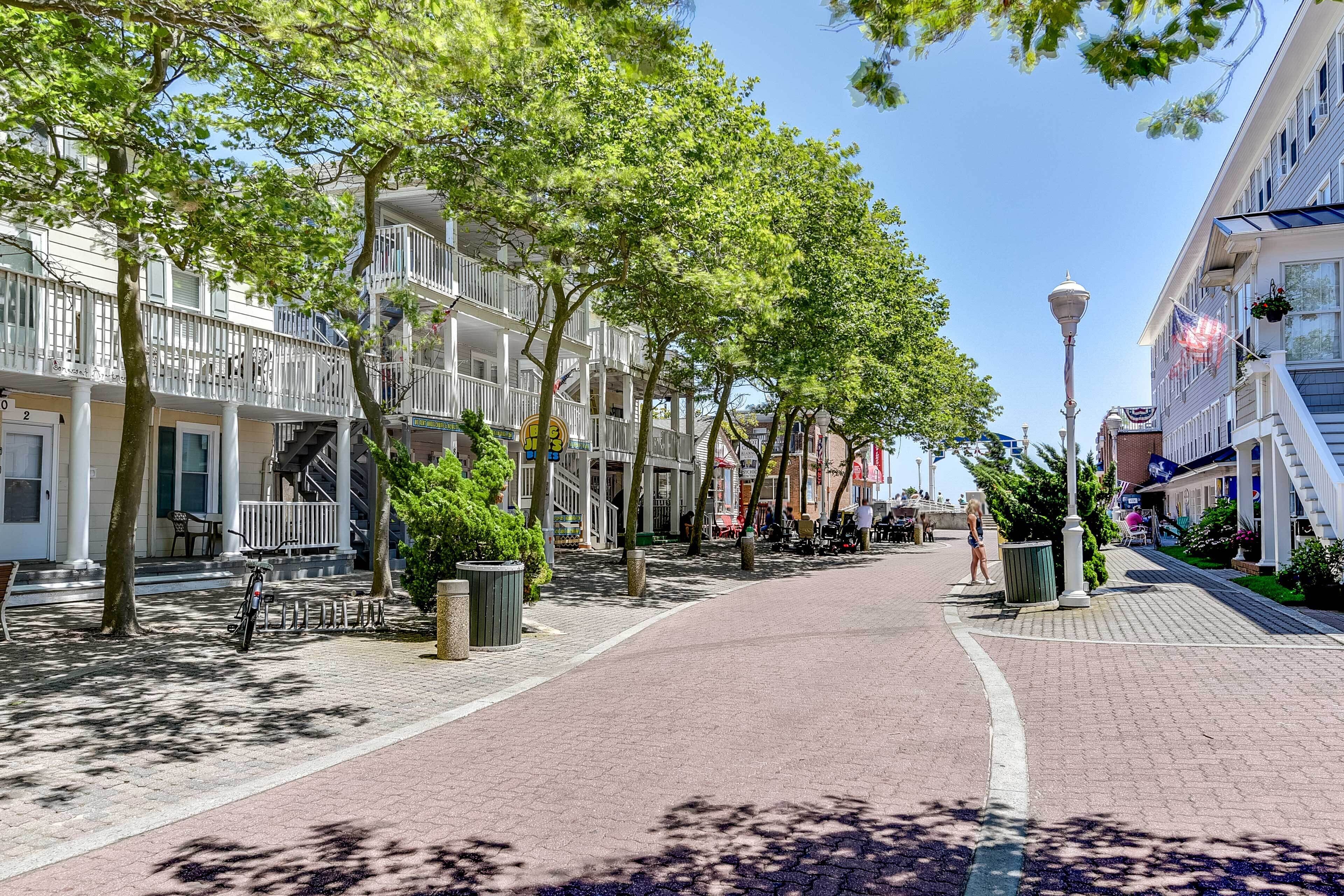 A tree-lined street with buildings on either side, a clear sky, and a pedestrian walkway.